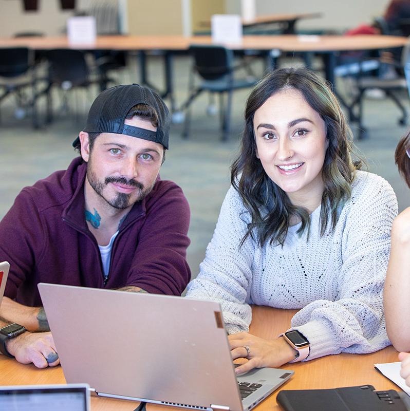 Two students discussing content on computer monitor at San Juan College